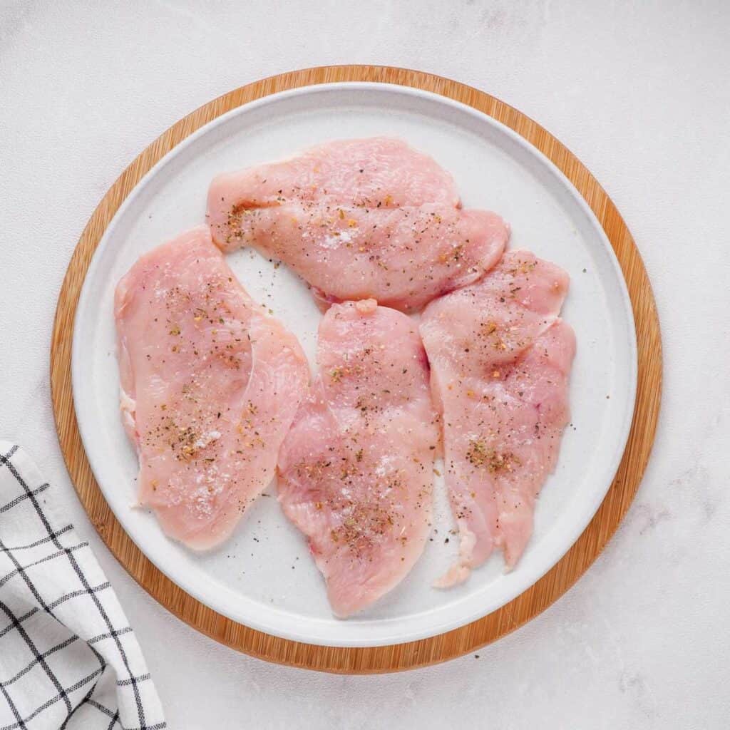 seasoned raw chicken breasts on white plate