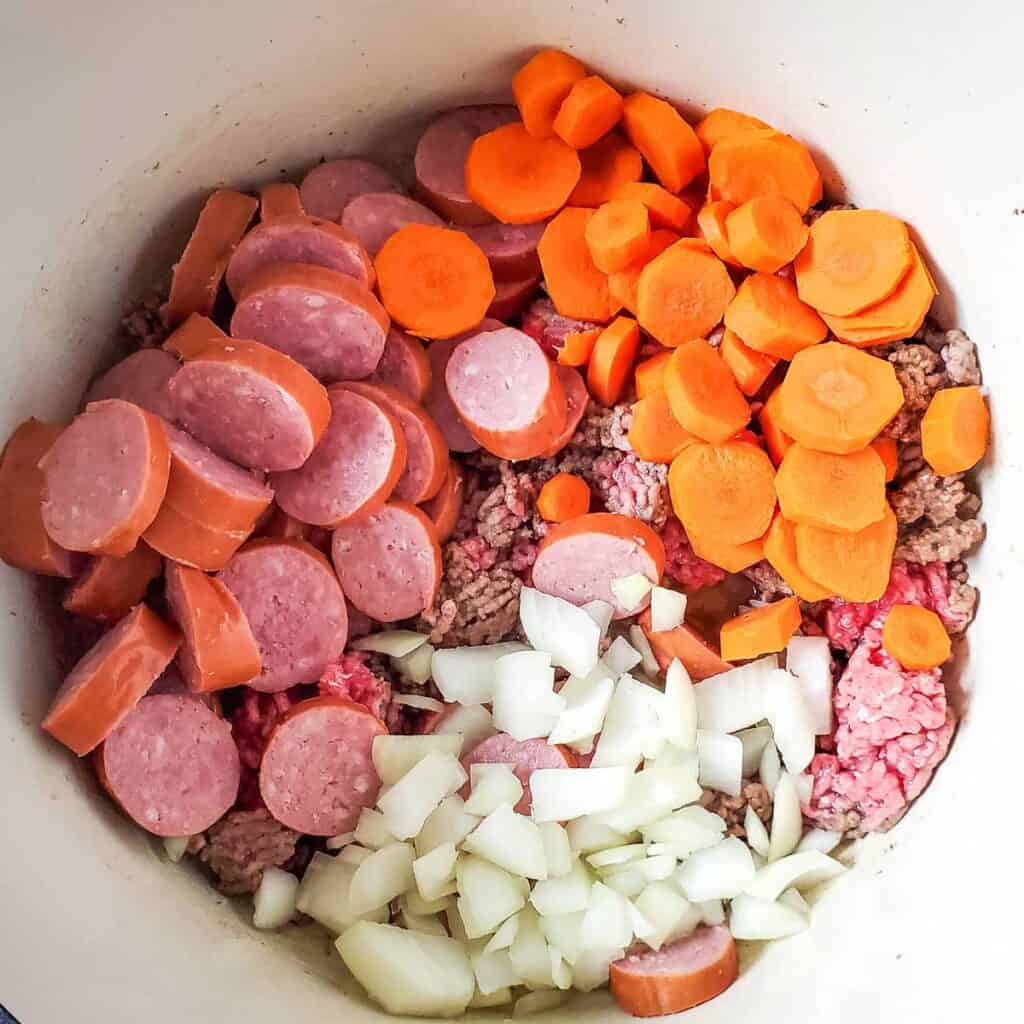 chopped sausage, carrots, and onion in dutch oven