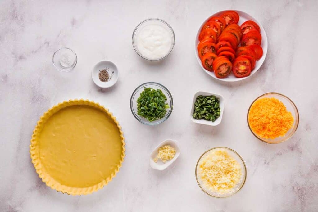 Southern tomato pie ingredients on marble countertop