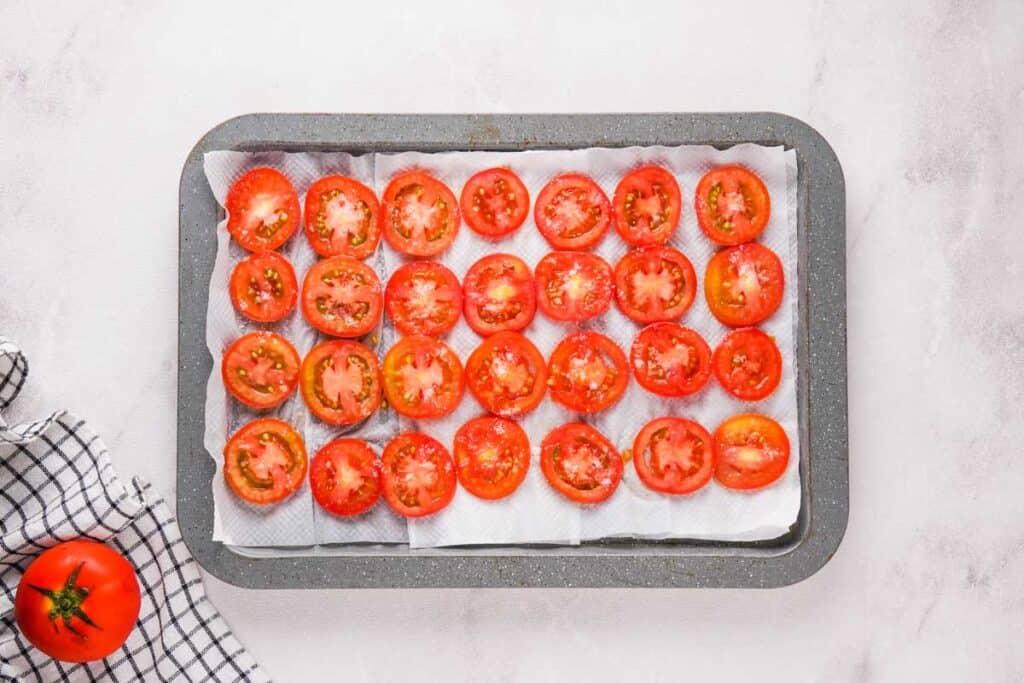 tomato slices on paper towels on baking sheet