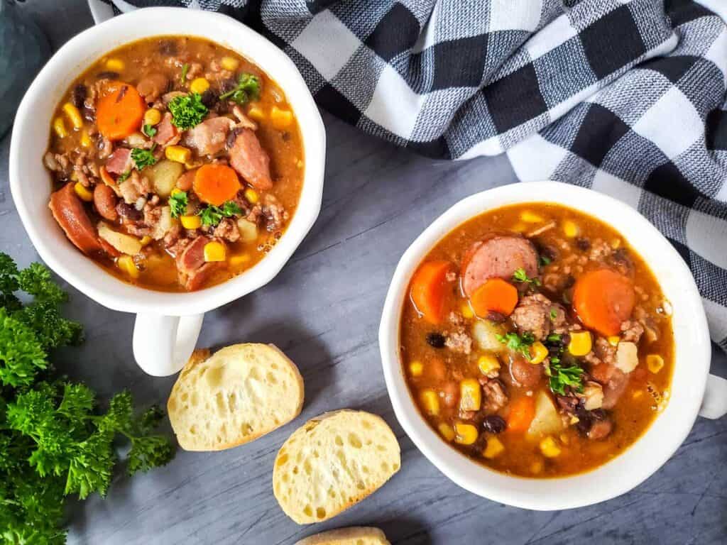 two bowls of cowboy stew with slices of bread