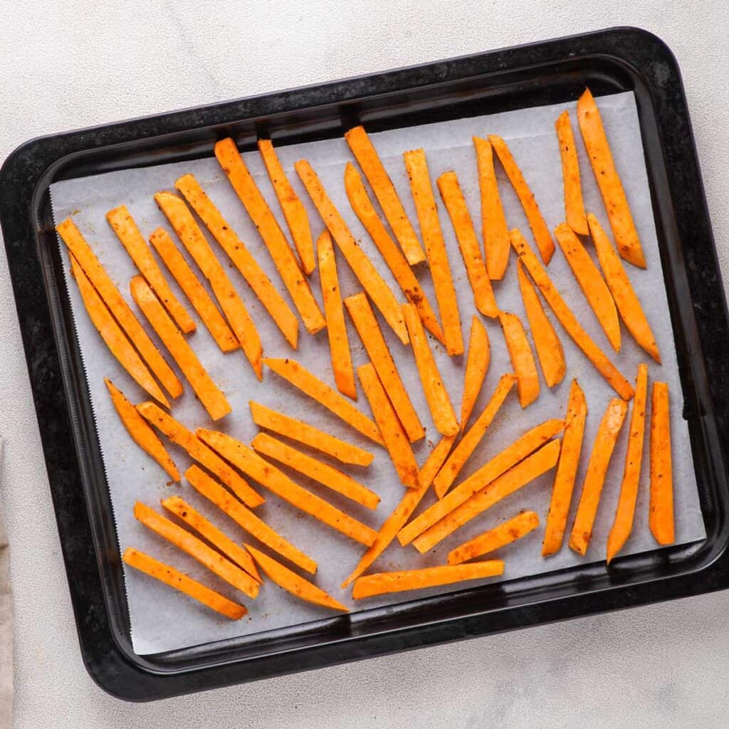 unbaked sweet potato fries on parchment paper lined baking sheet