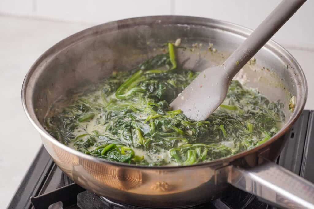 spatula stirring creamed spinach as it cooks
