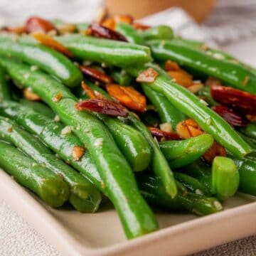 close up of green beans almondine on rectangle plate