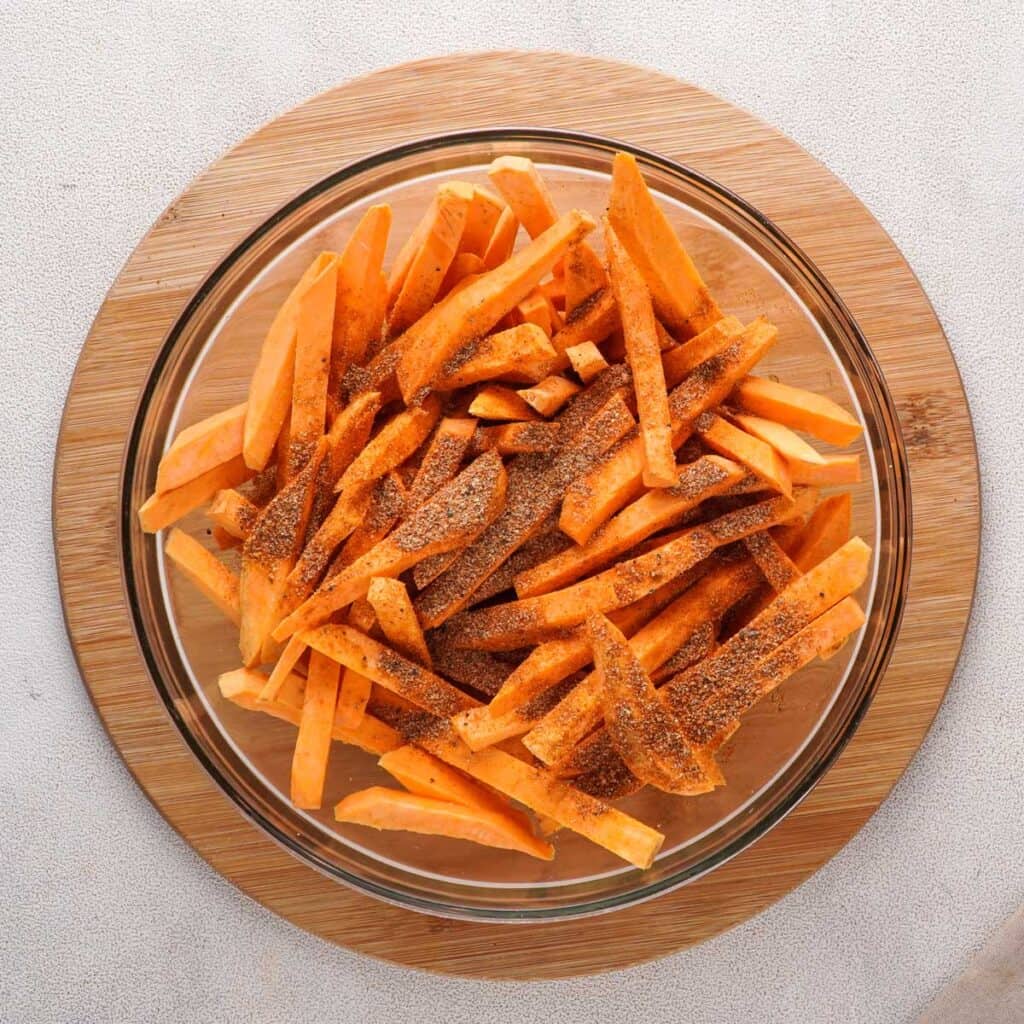 sweet potato fries with spices on top in glass bowl