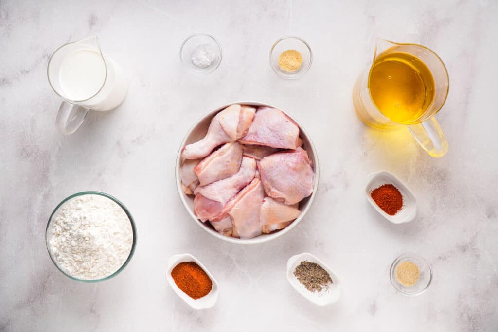 Southern fried chicken ingredients in bowls on marble countertop