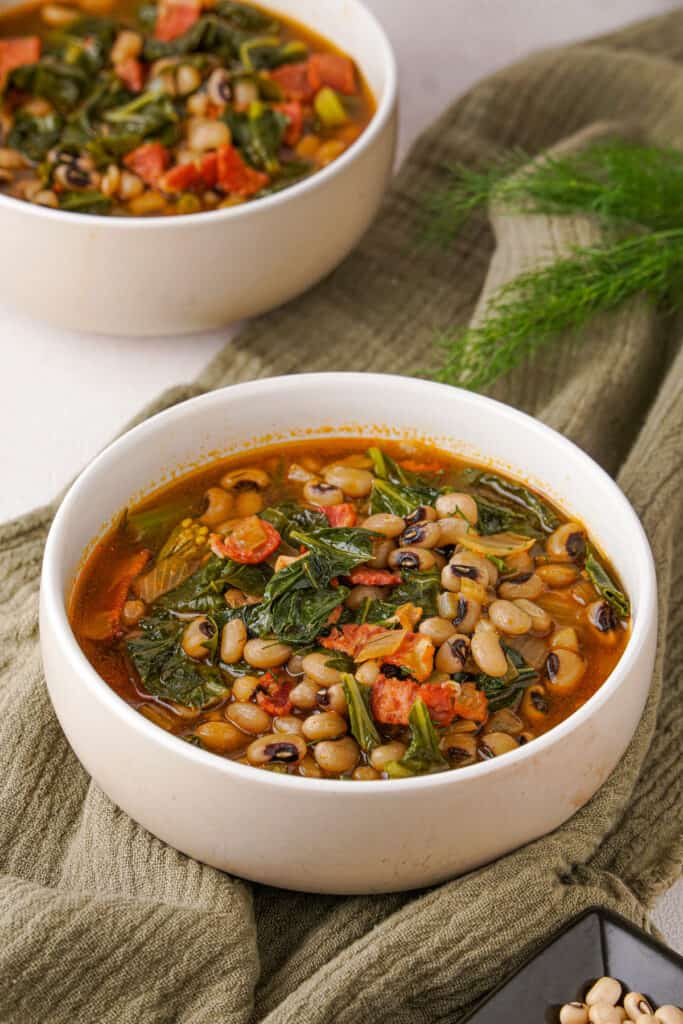 black-eyed peas and greens in two white bowls