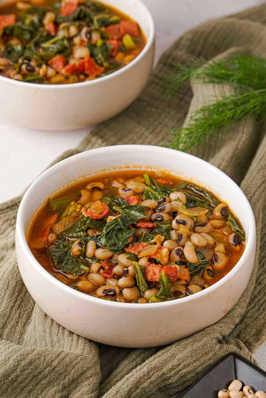 Black-eyed peas and greens in two white bowls.