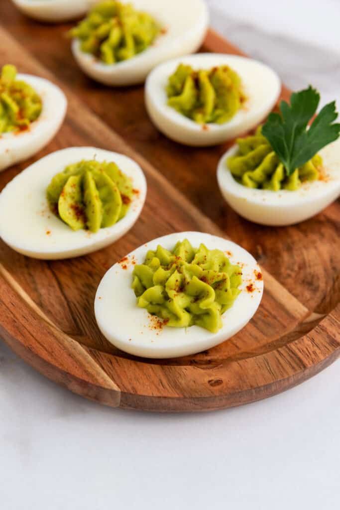 close up of avocado deviled eggs on wood tray