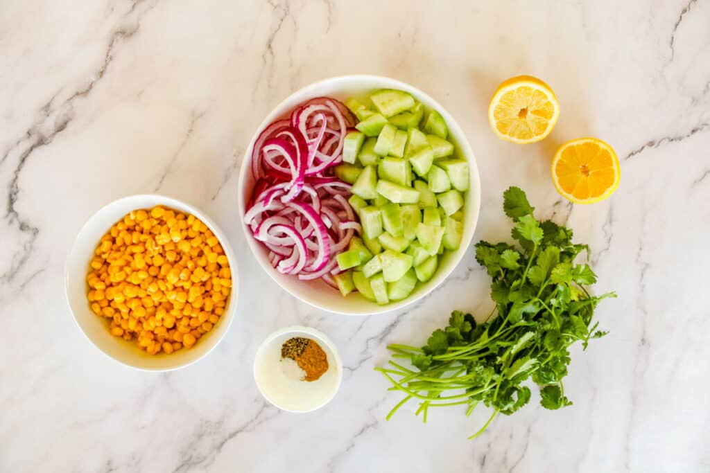 cucumber corn salad ingredients in bowls on countertop