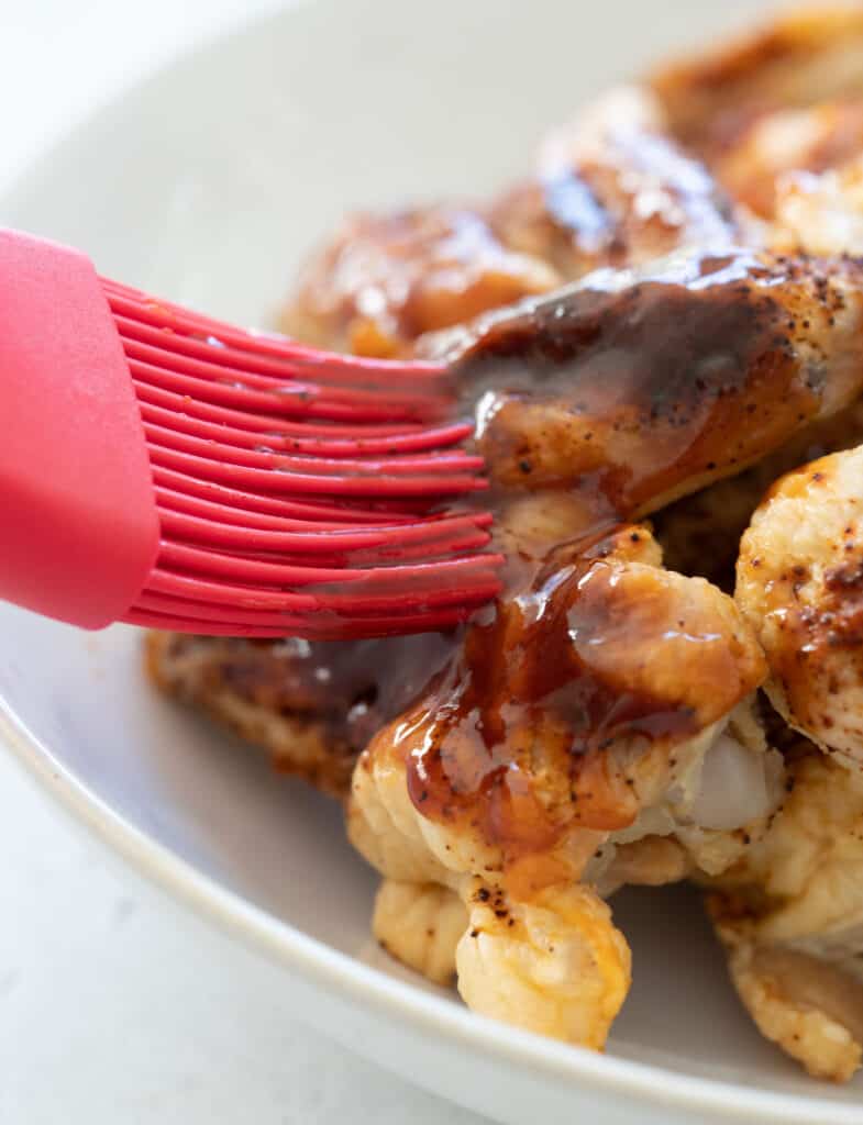 brushing chicken wings with bourbon bbq sauce