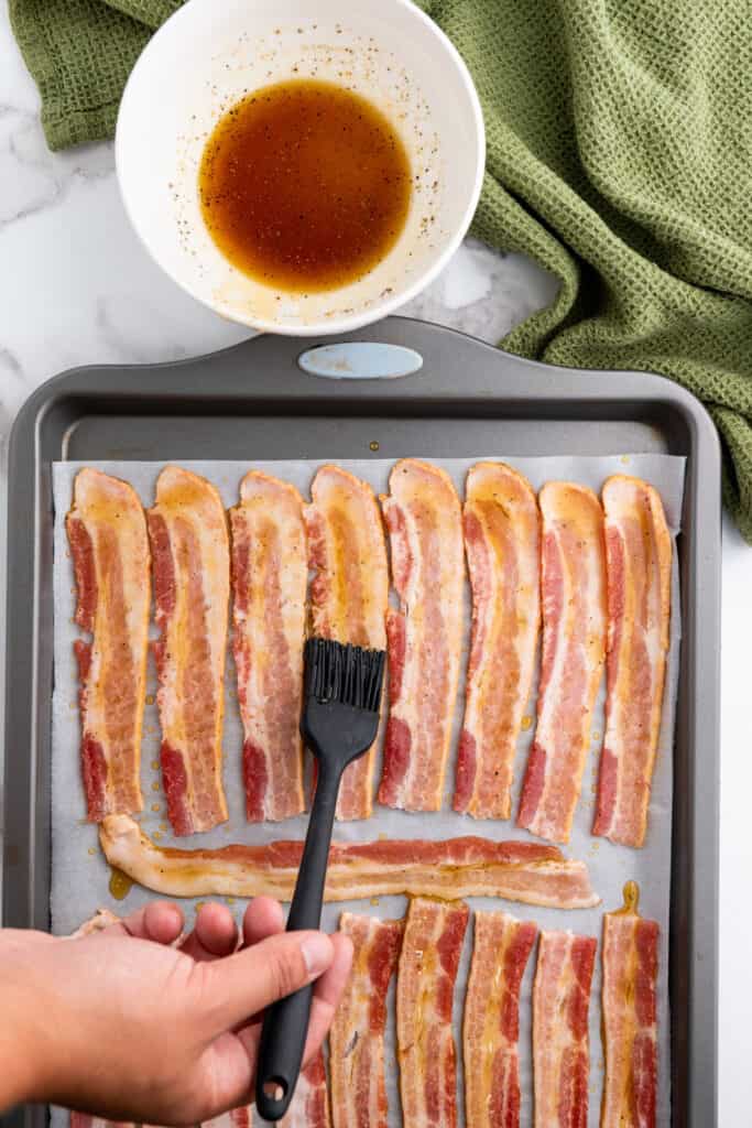 brushing raw bacon with maple syrup