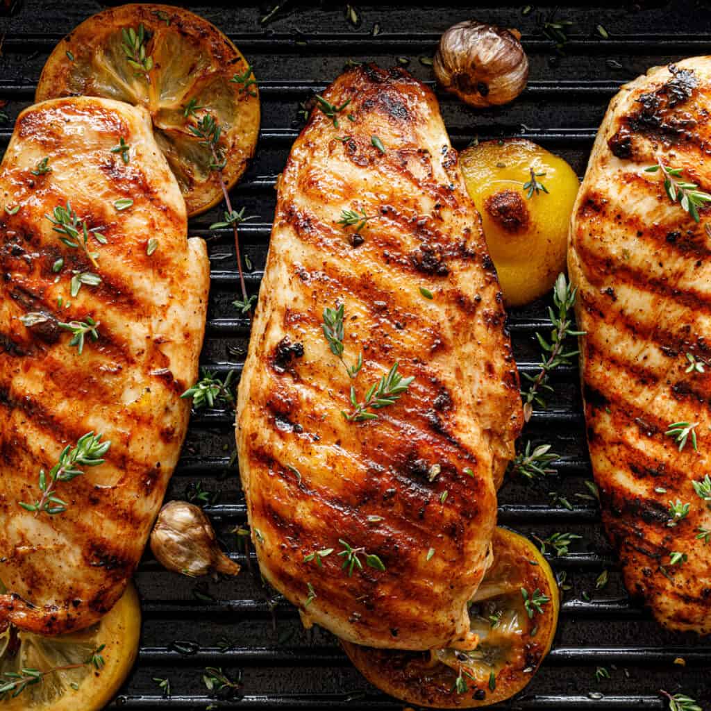 grilled chicken with lemon and herbs on grill