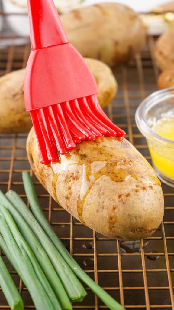 brushing butter onto a russet potato
