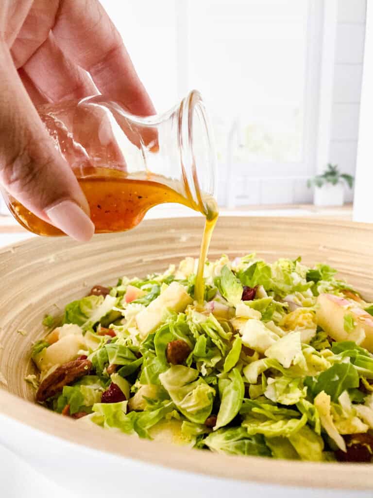 pouring dressing on brussels sprouts salad