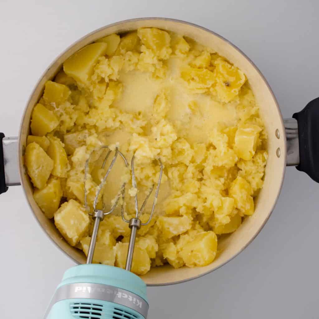 mixer in pot of potato pieces