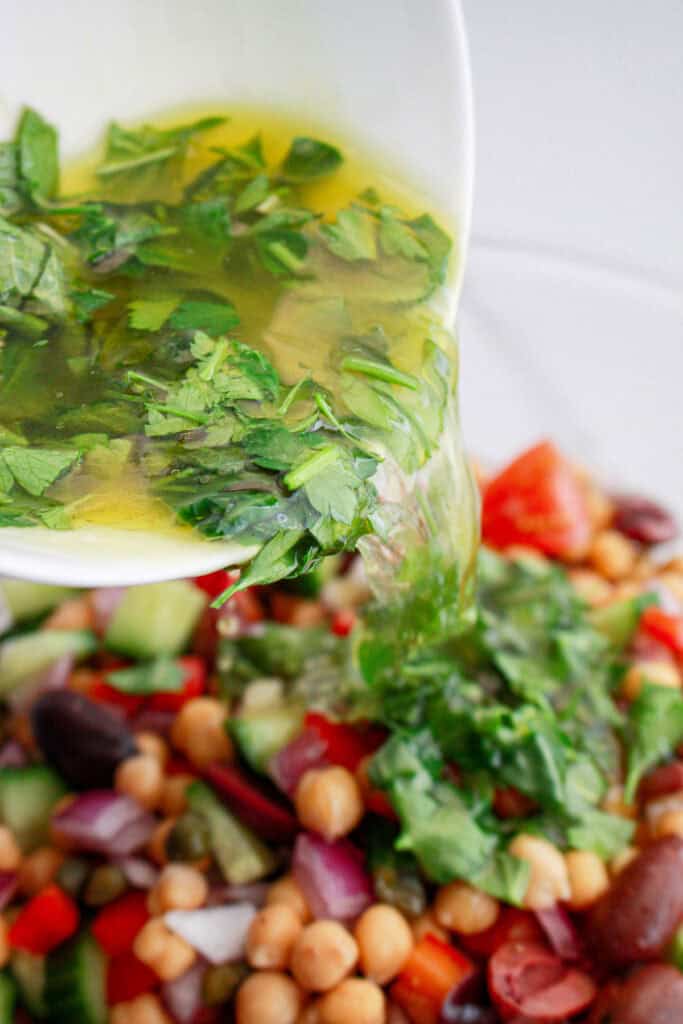 pouring dressing over Mediterranean Chickpea Salad