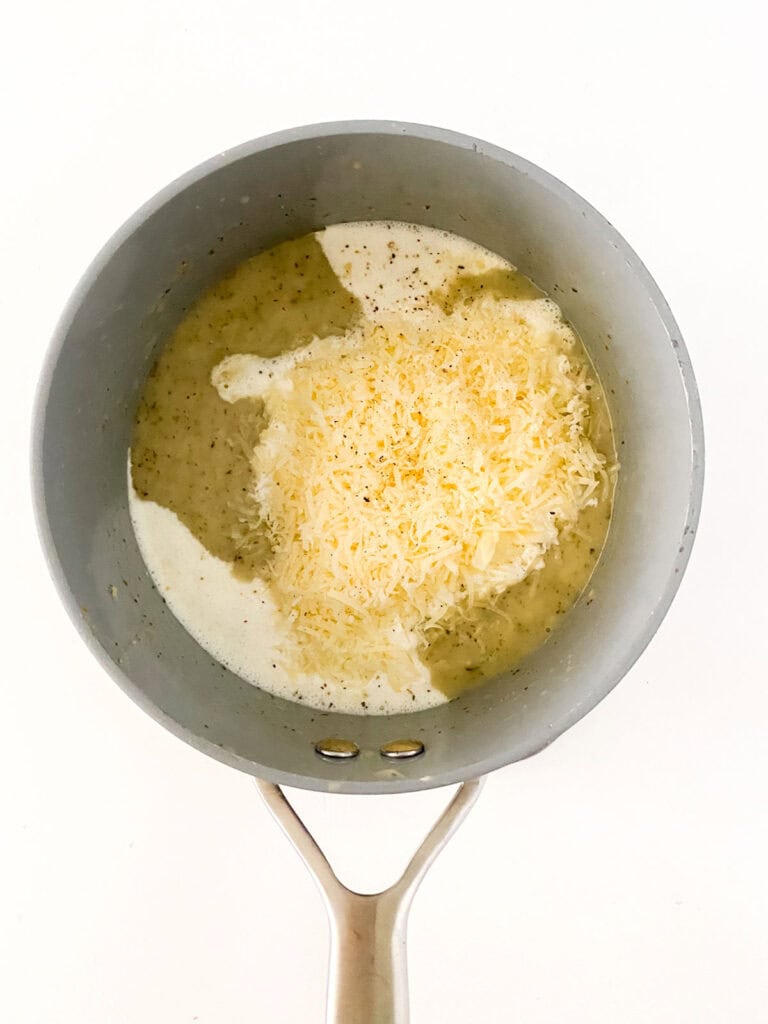 adding cheese to garlic parmesan sauce