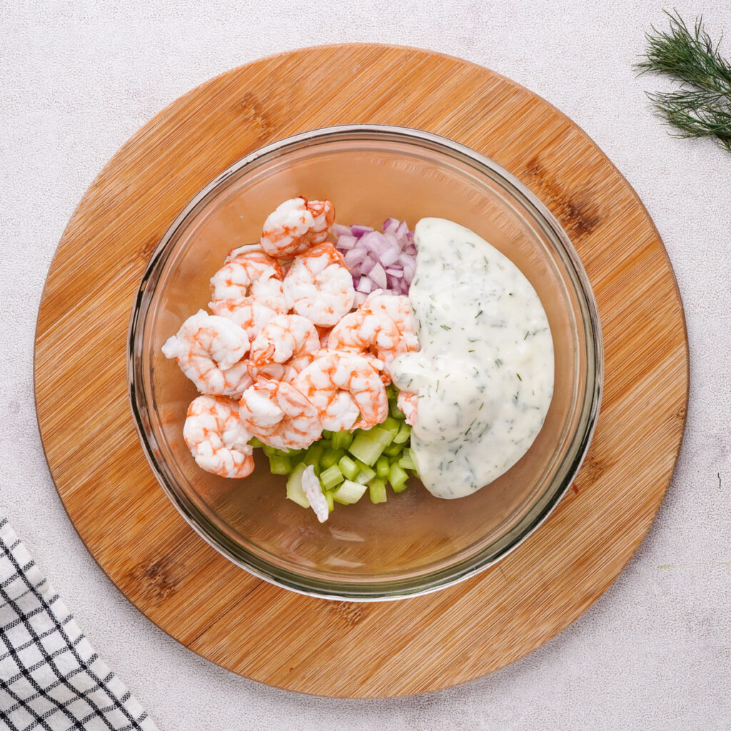 Shrimp salad ingredients in glass bowl before mixing