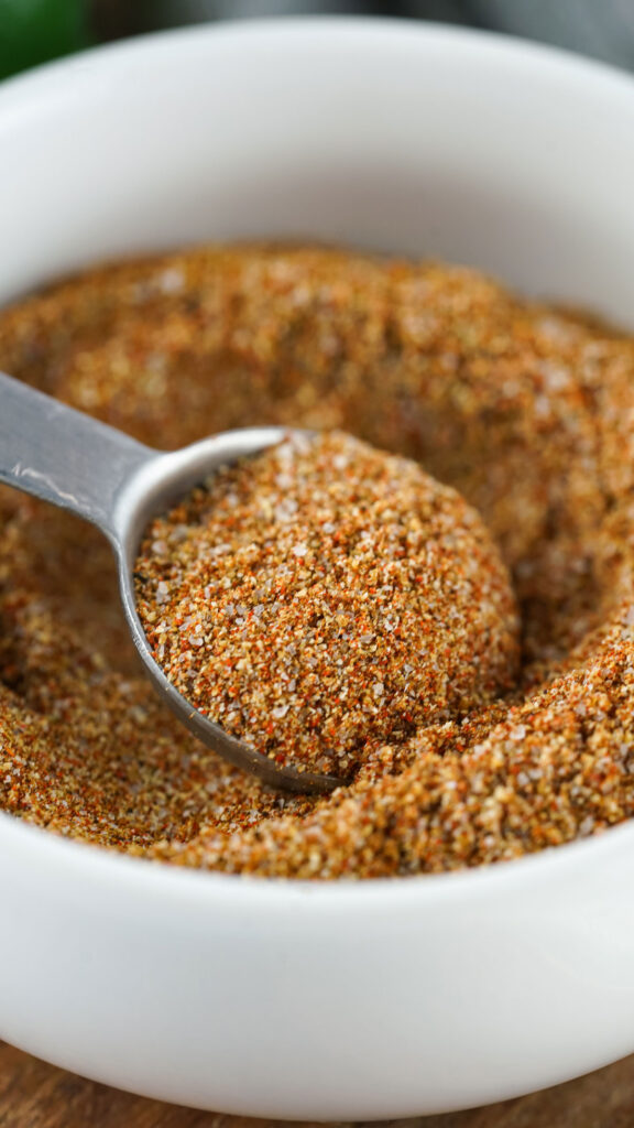 white bowl of fajita seasoning and spoon scooping some