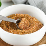 spoon scooping fajita seasoning from white bowl
