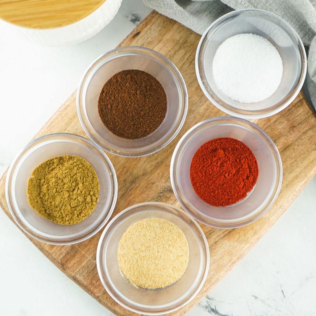 fajita seasoning ingredients in glass bowls on cutting board