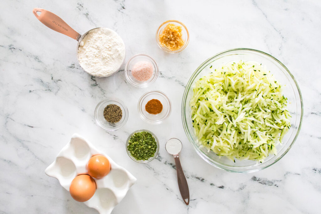 zucchini fritters ingredients on marble countertop