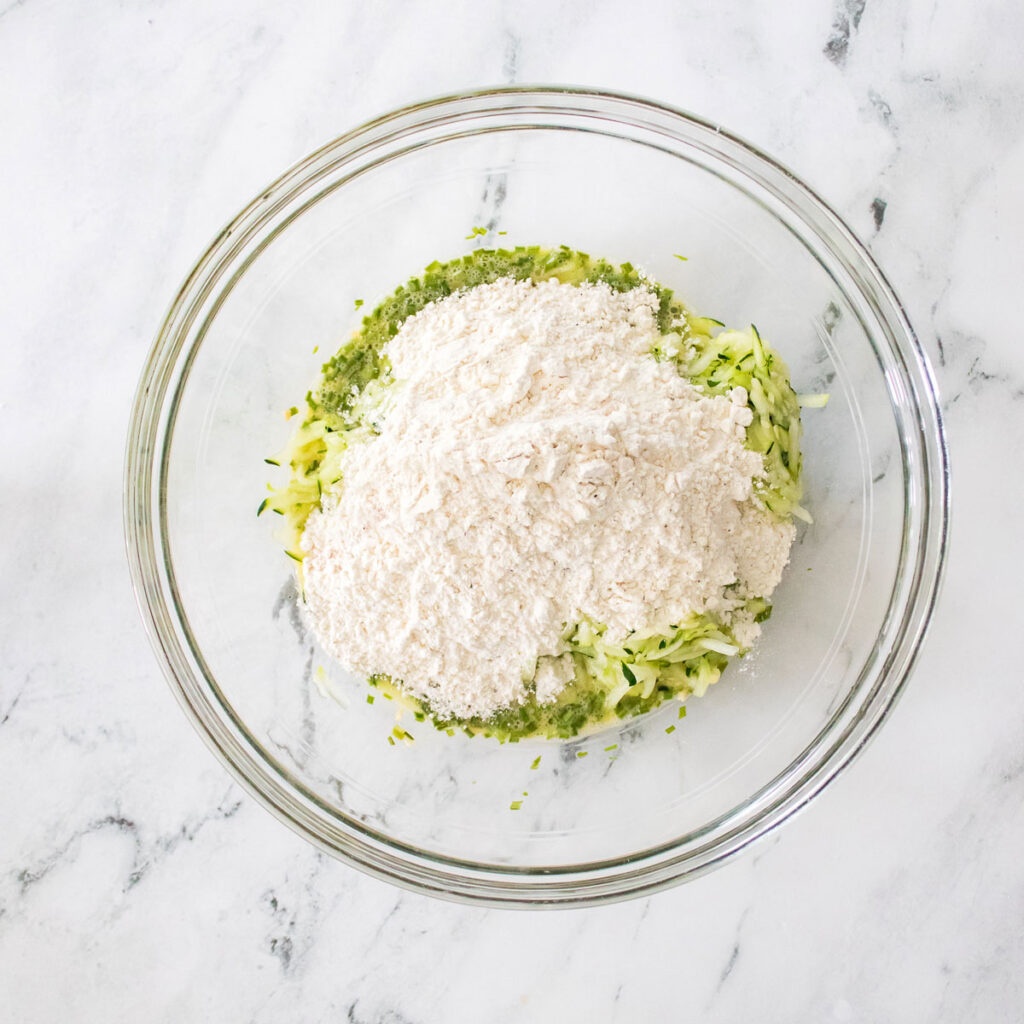 flour and spiralized zucchini in glass bowl