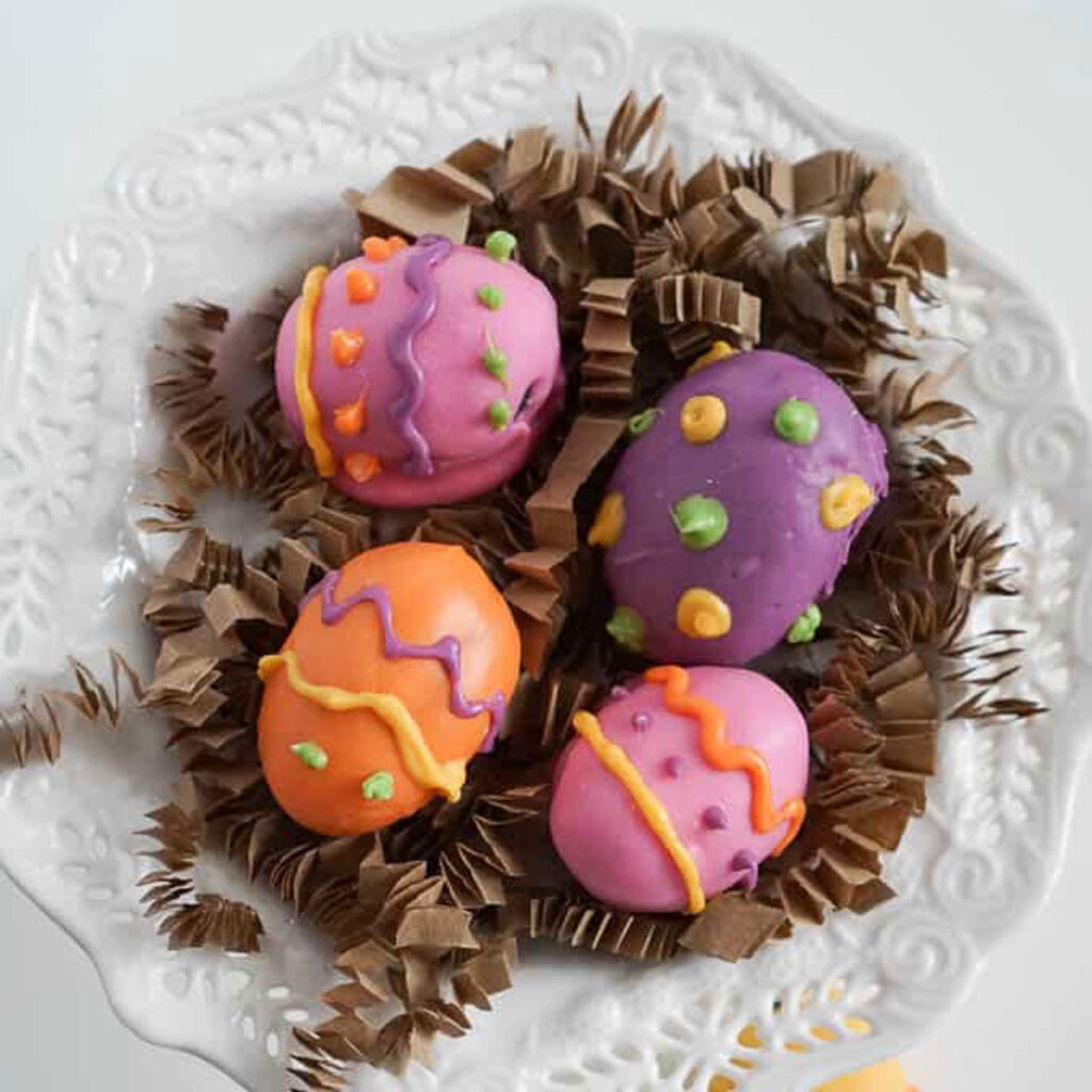 Easter egg Oreo truffles on white dish with kraft crinkled paper