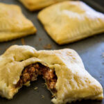 sloppy joe pockets on baking sheet with one cut open