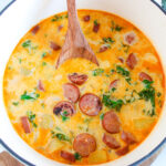 sausage potato kale soup in dutch oven with wooden spoon