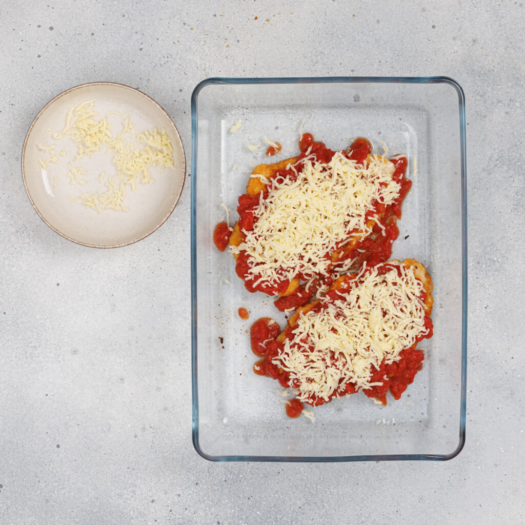 chicken parmesan in glass dish before baking