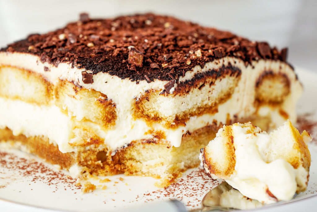 close up of serving of tiramisu with one bite removed
