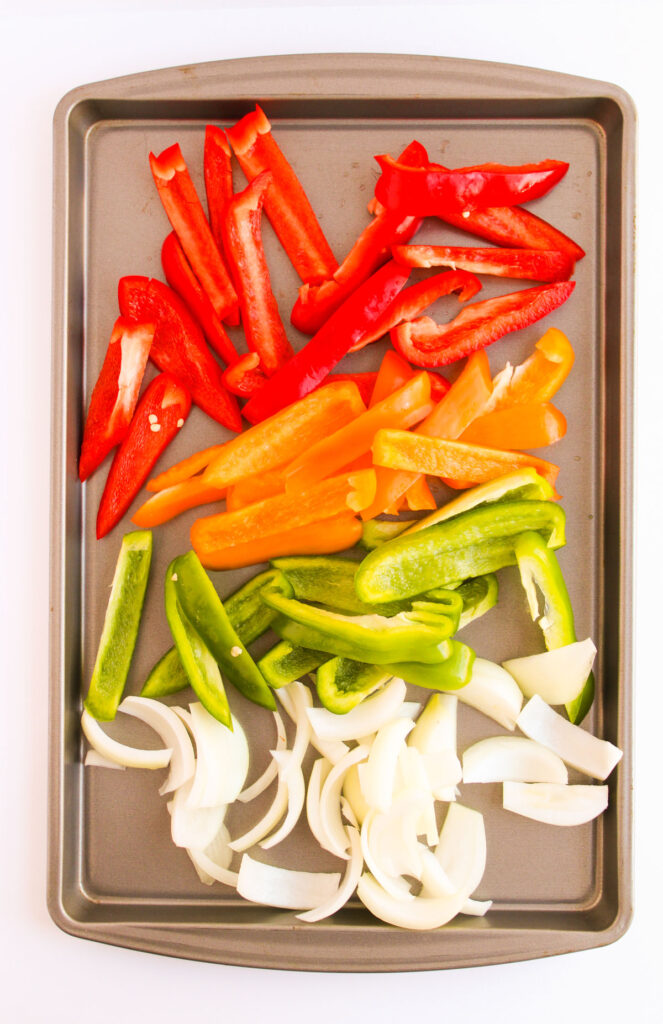 sliced peppers and onions on sheet pan