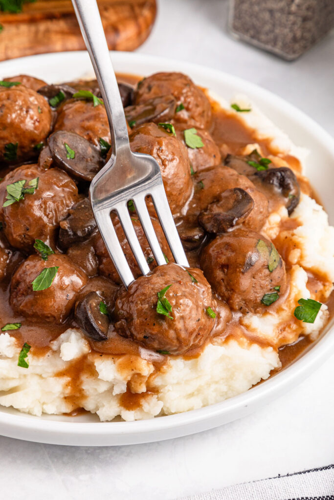 fork in Salisbury Steak Meatballs on mashed potatoes