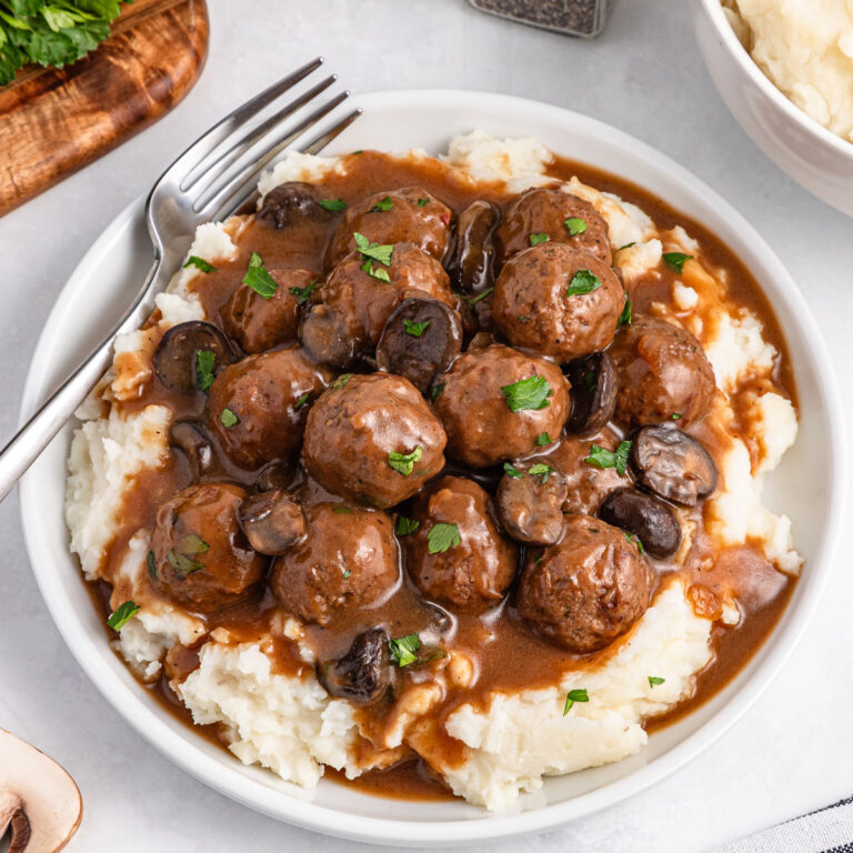 Salisbury Steak Meatballs over mashed potatoes on white plate