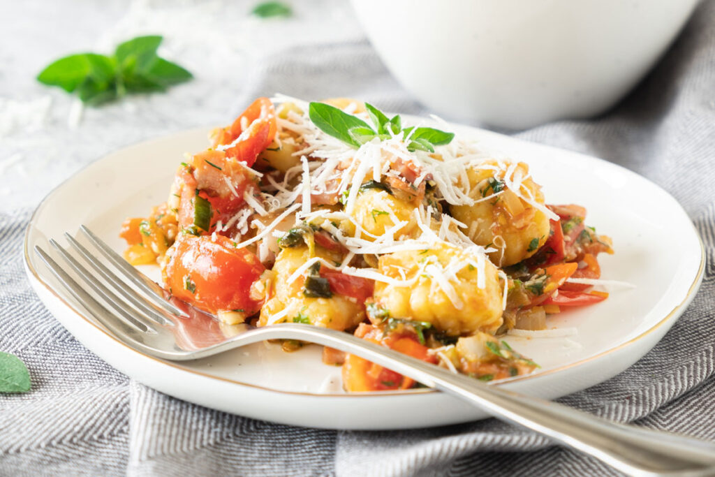 bacon gnocchi on white plate with fork