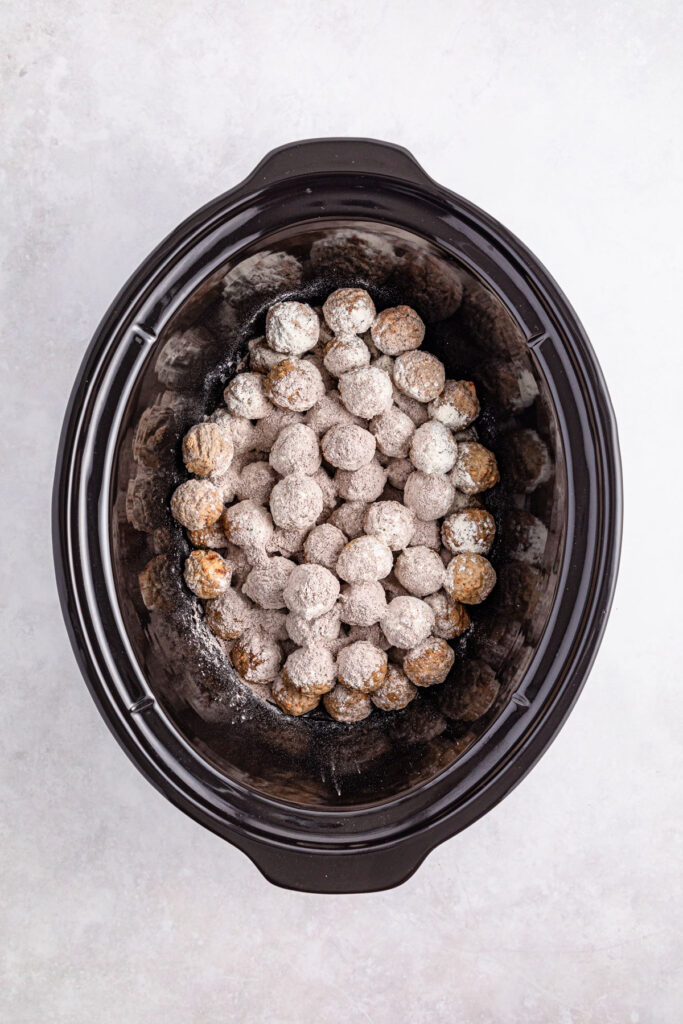 frozen meatballs in slow cooker with seasoning sprinkled on top