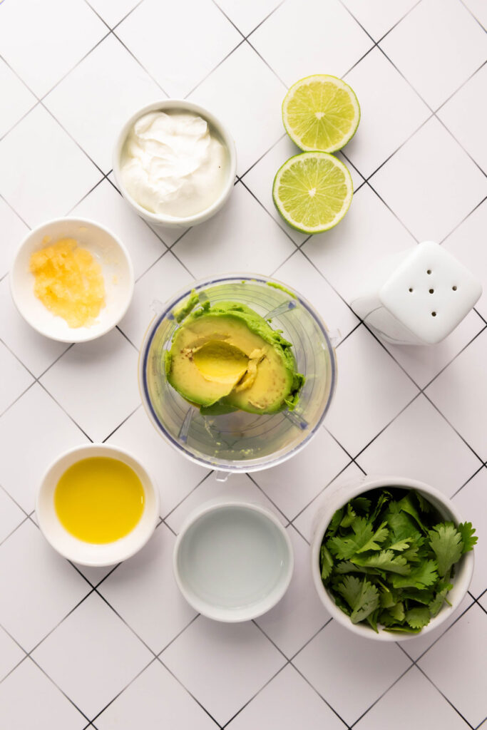 avocado sauce ingredients in bowls surrounding food processor