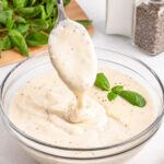 spoon dripping bechamel sauce into glass bowl