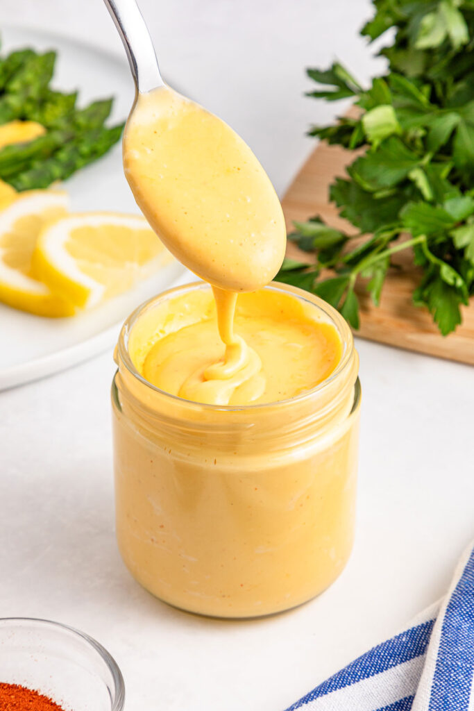 spoon pouring hollandaise sauce into jar