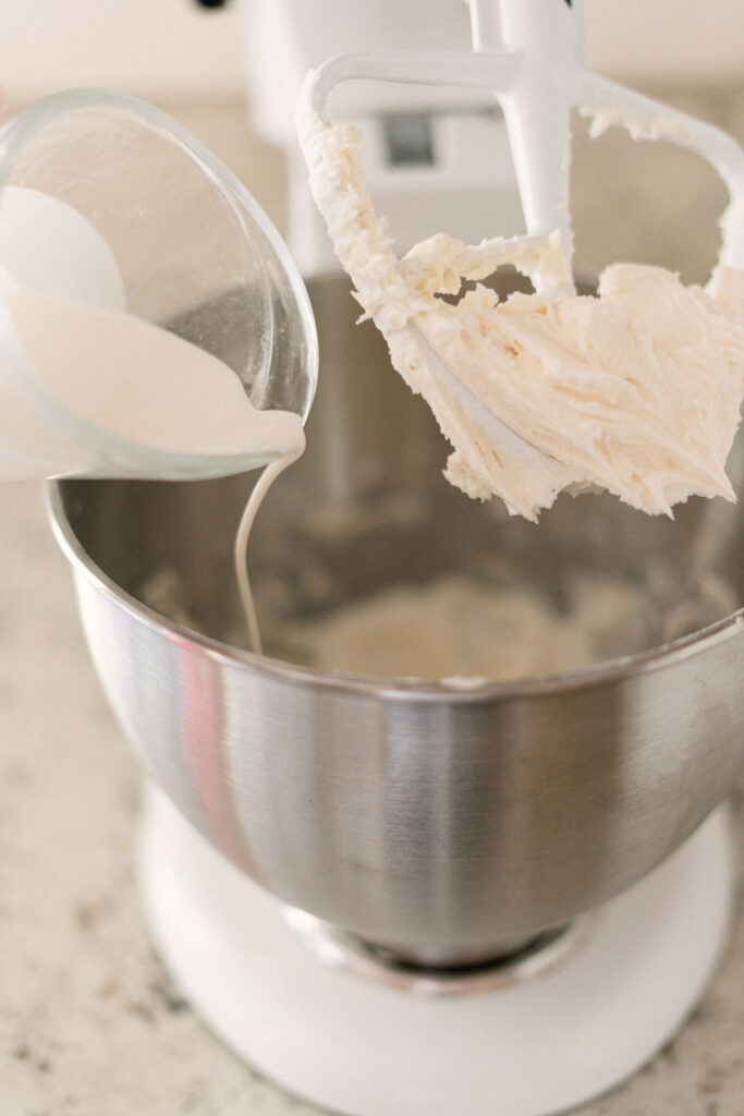 pouring milk into mixer to make frosting