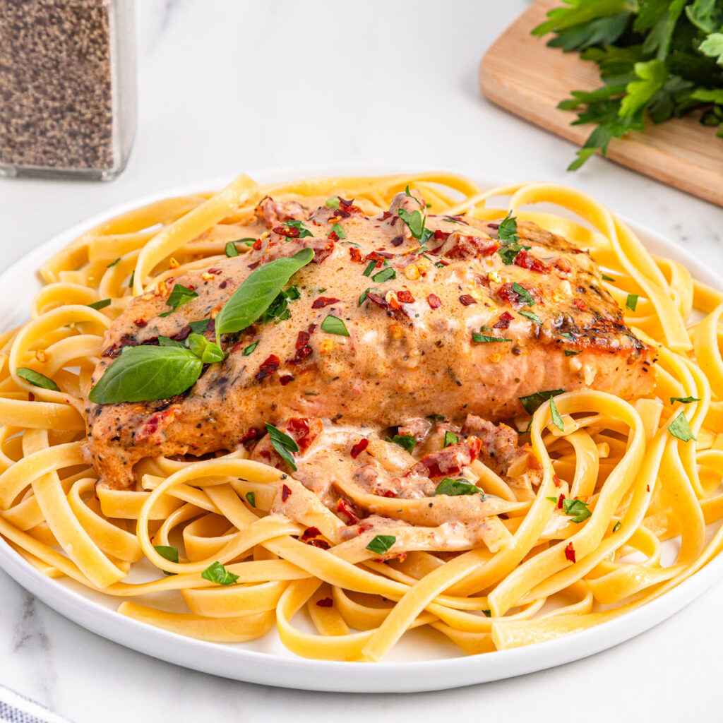 marry me salmon over linguine on white plate