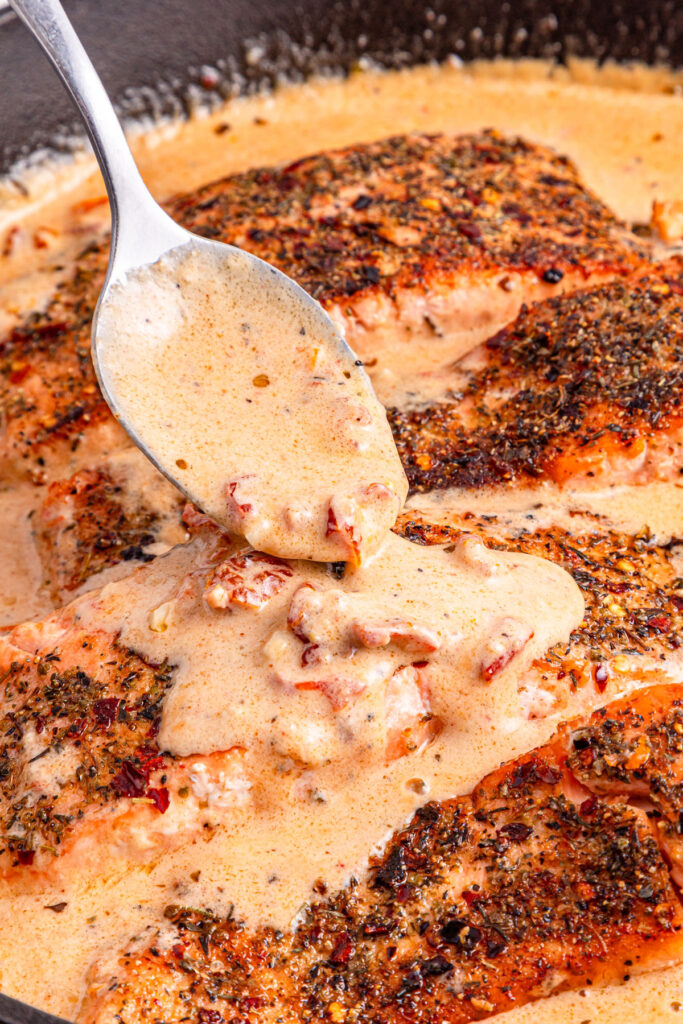 spooning sauce over marry me salmon