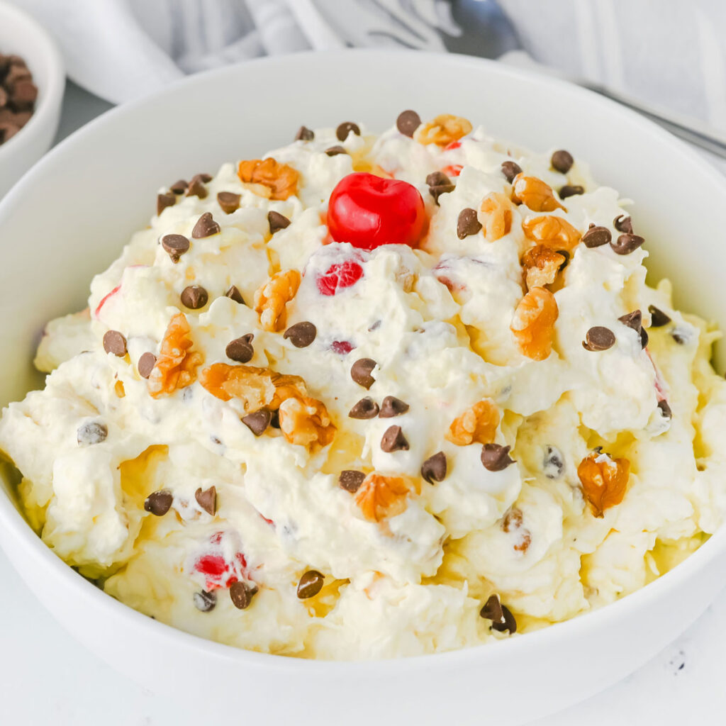 banana split fluff salad in white bowl with cherry on top
