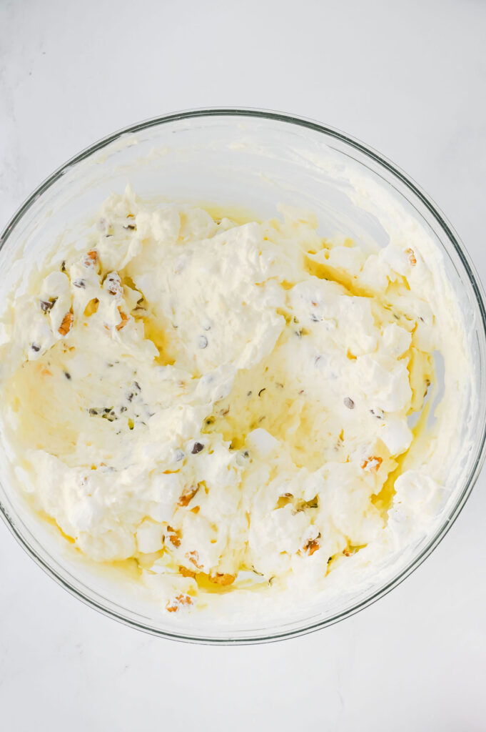 mixing banana split fluff salad in glass bowl