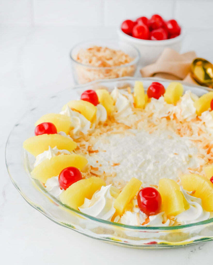 pina colada pie in glass dish with sliced pineapple and cherries on top