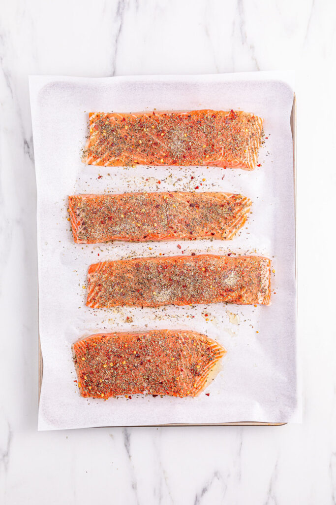salmon with seasoning on parchment paper