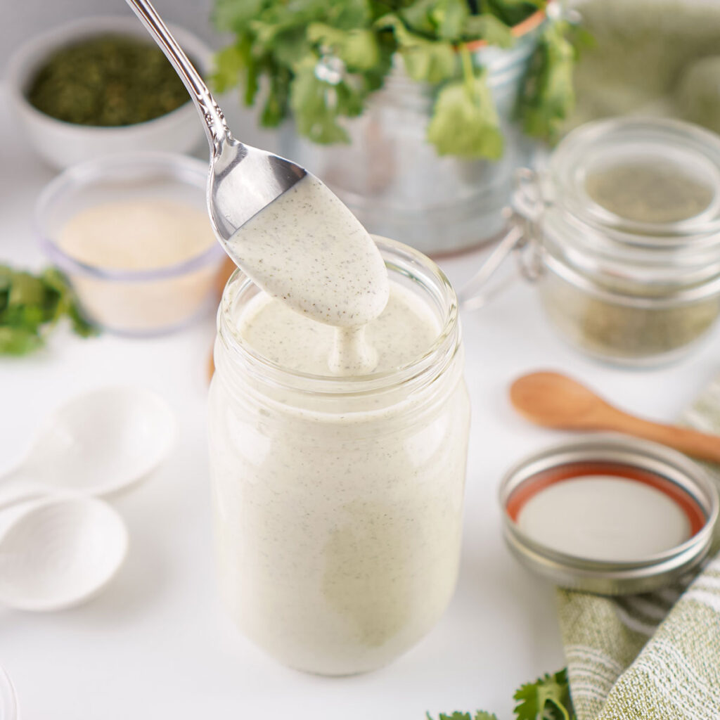 spoon dripping homemade ranch from glass jar