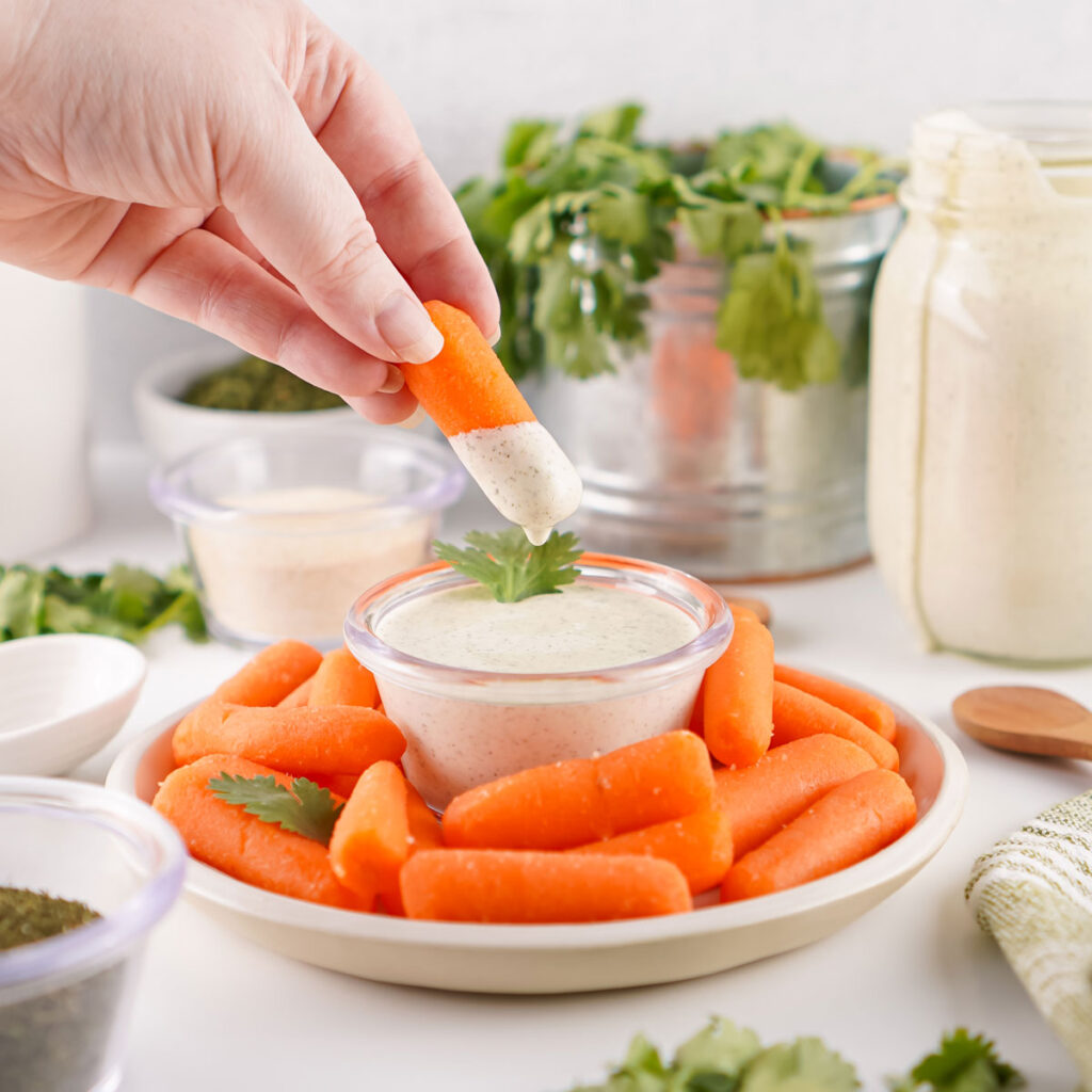 hand dipping carrot in homemade ranch dressing